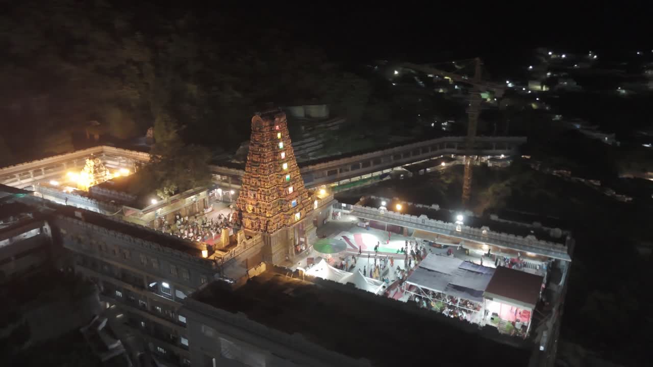 An aerial video of Kanaka Durga Temple in Vijayawada at night.The temple's golden gopuram, illuminated by countless lights, would create a celestial glow against the inky blackness of the sky.