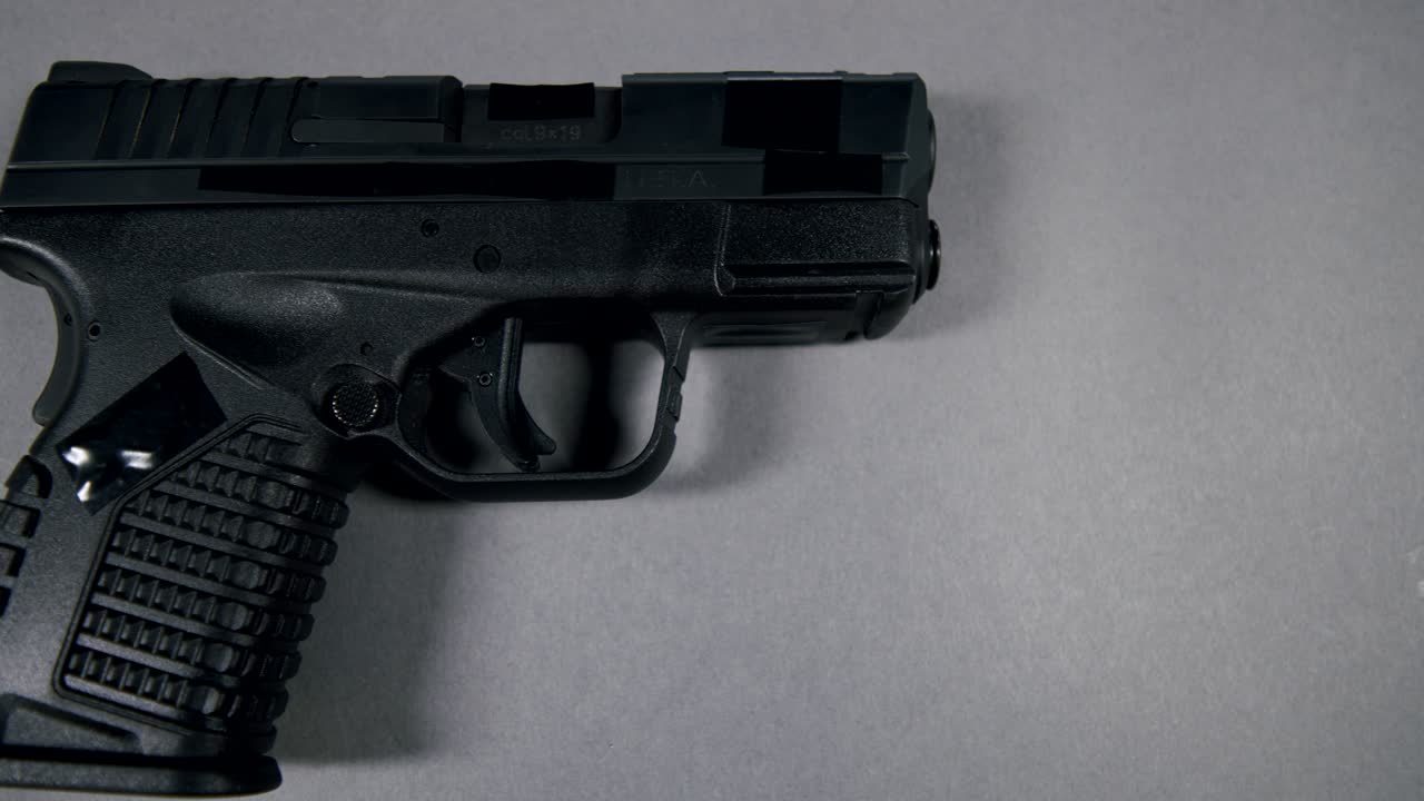 black Semi-Automatic 9mm Handgun on gray background, right hand side view, slow pan right to left, 4k