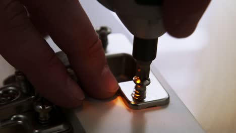 Caucasian-hands-put-a-hinge-into-a-socket-of-a-glass-cabinet