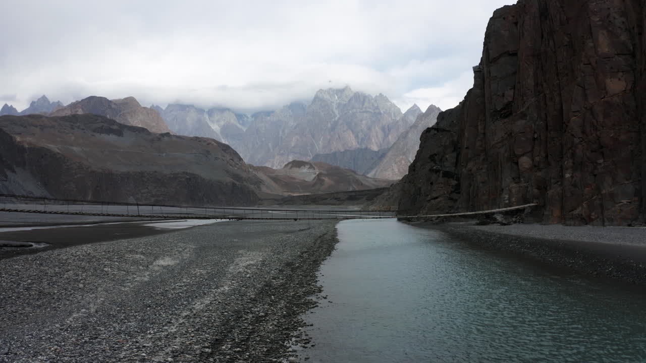 toma de drones del puente colgante hussaini sobre el río hunza en las montañas nubladas del himalaya