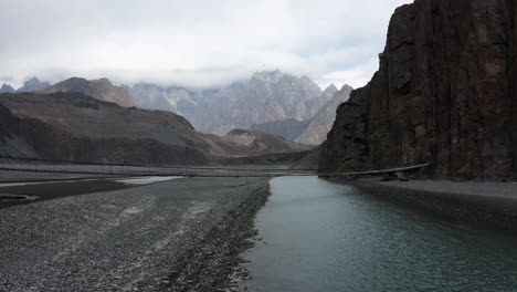 Drone-shot-of-Hussaini-Suspension-Bridge-over-the-Hunza-River-in-cloudy-Himalaya-mountains