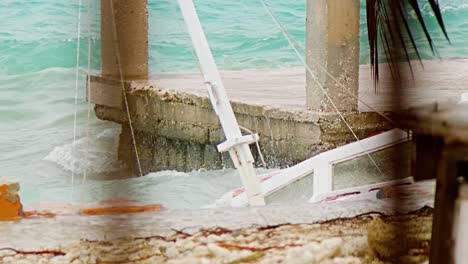 close up of local wooden fishing boat being smashed into pieces during sudden storm with rough waves, caribbean
