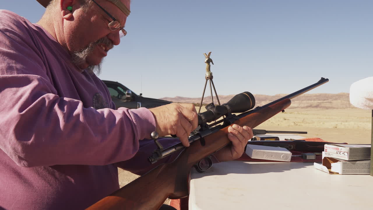 총 범위에서 그의 소총 범위를 조정하는 남자