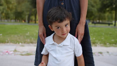 lindo y divertido niño parado junto a mamá al aire libre