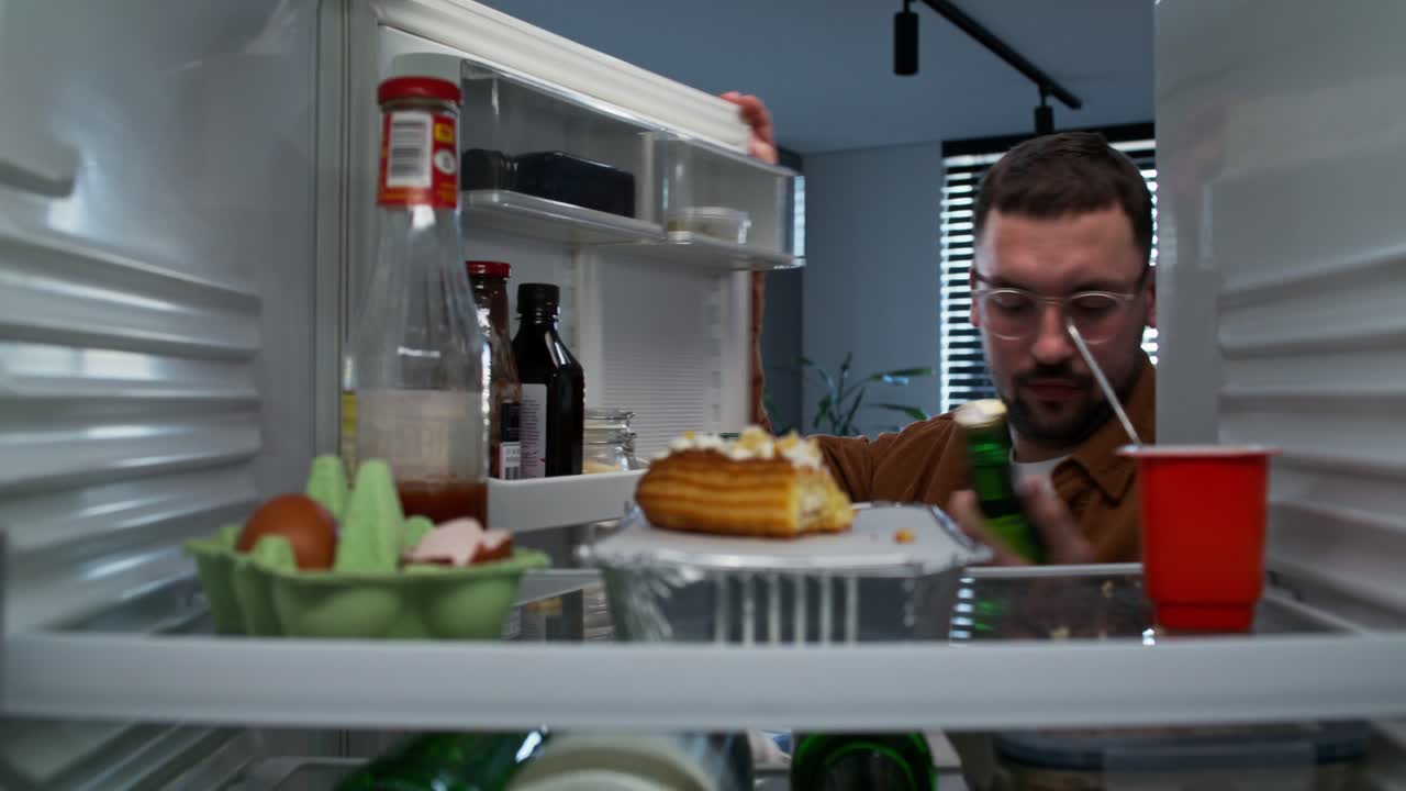 hombre mirando dentro de un refrigerador abierto