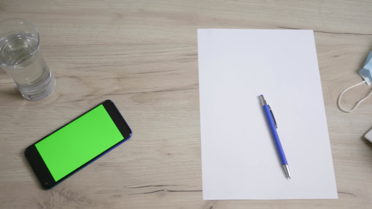Top view from above a table with papers and coffee ready to work, office before working hours. Phone on the table, green screen.