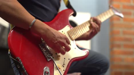 man musician playing a pick on a red electric guitar