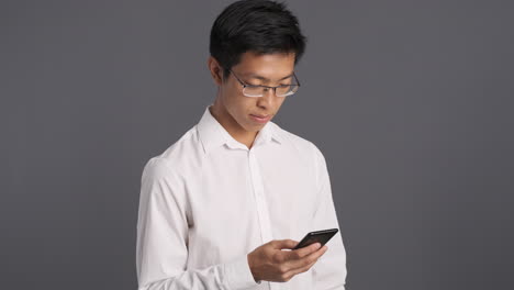 pensive asian man using smartphone.