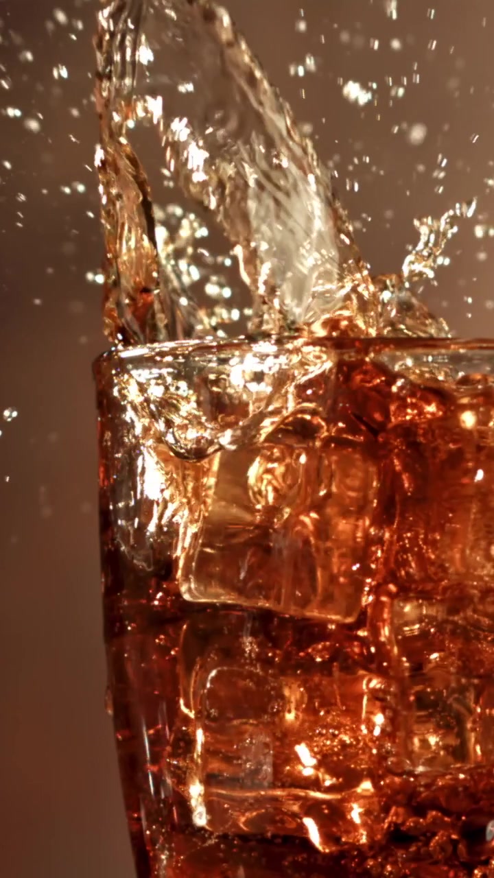 Cubetto di ghiaccio che schizza in un bicchiere di soda al rallentatore