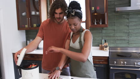 Pareja-Diversa,-Un-Joven-Caucásico-Y-Una-Mujer-Afroamericana,-Compostando-Juntos-Residuos-De-Alimentos-