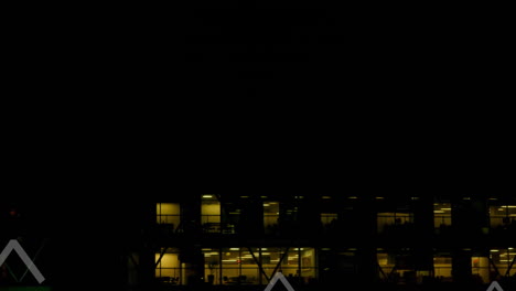 Animation-of-multiple-up-arrows-over-aerial-view-of-illuminated-modern-building-against-night-sky