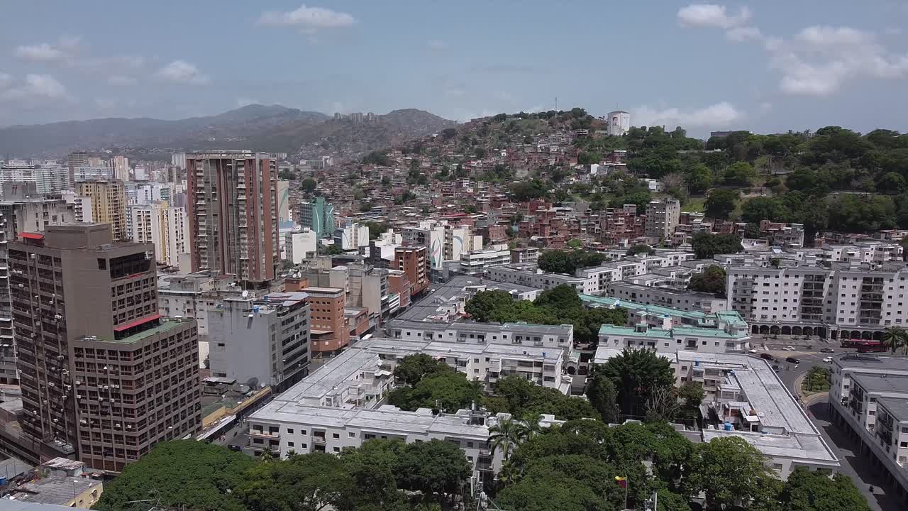 ascenso aéreo diurno sobre el centro de caracas, capital de venezuela, que muestra el horizonte de la ciudad y las montañas más allá
