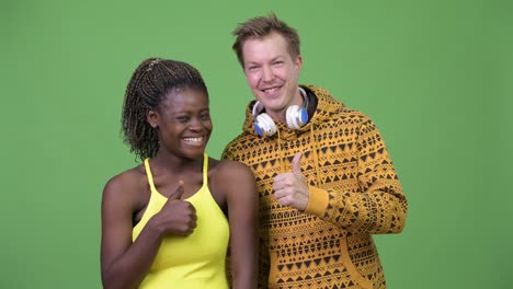 young multi-ethnic couple giving thumbs up together