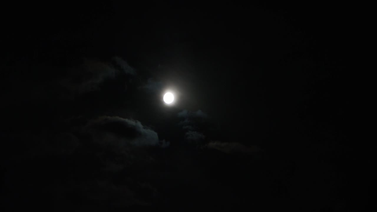 una toma en tiempo real de la luna y las nubes por la noche