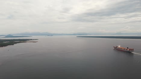 Landscape-with-cargo-ship-sailing-through-Paranagua-Bay-heading-to-the-port,-Paraná,-Brazil