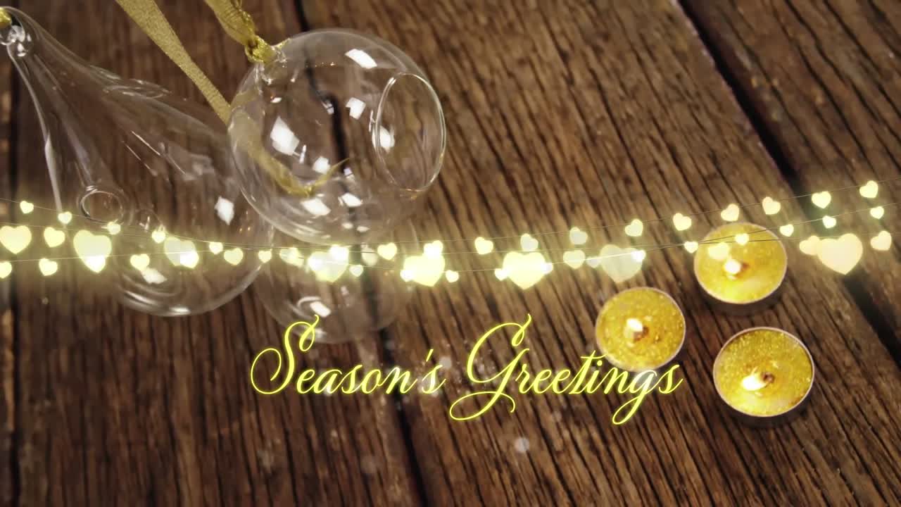 Animation of text, season's greetings, in yellow, string lights, candles and christmas decorations