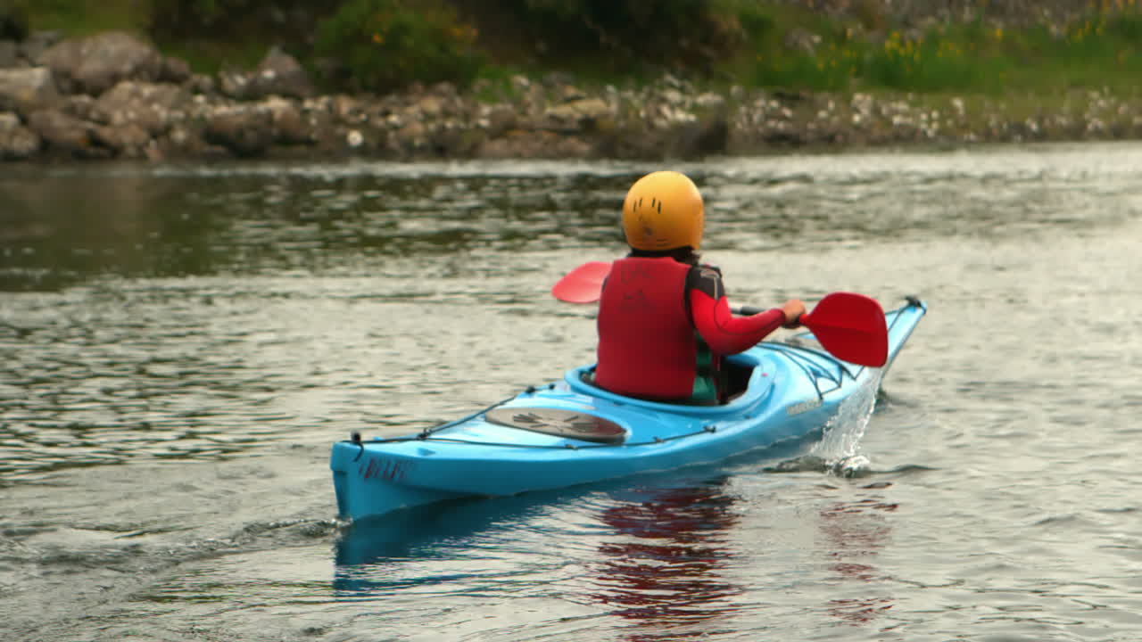 Woman kayaking in a river away from the camera