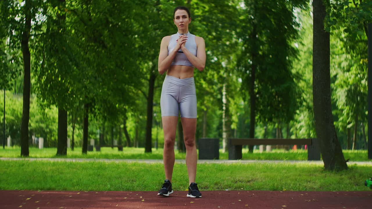 Female athlete performs side lunges work out her legs in the Park in slow motion. Beautiful woman playing sports in the Park.