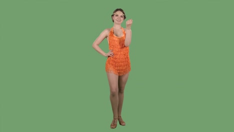 a beautiful woman looks at the camera, waves her hand coquettishly and showing gesture come here. portrait of a brunette in an orange dress with fringe on a green screen in the studio. slow motion