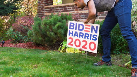 young man removes joe biden kamala harris 2020 yard sign in front yard of house, political support