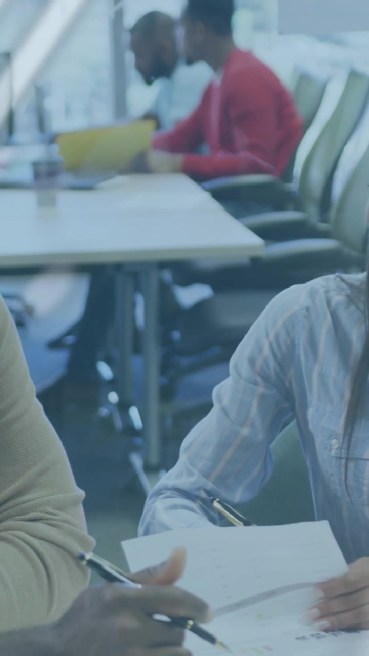 Animation of multiple graphs and globe over multiracial colleagues analyzing documents on desk