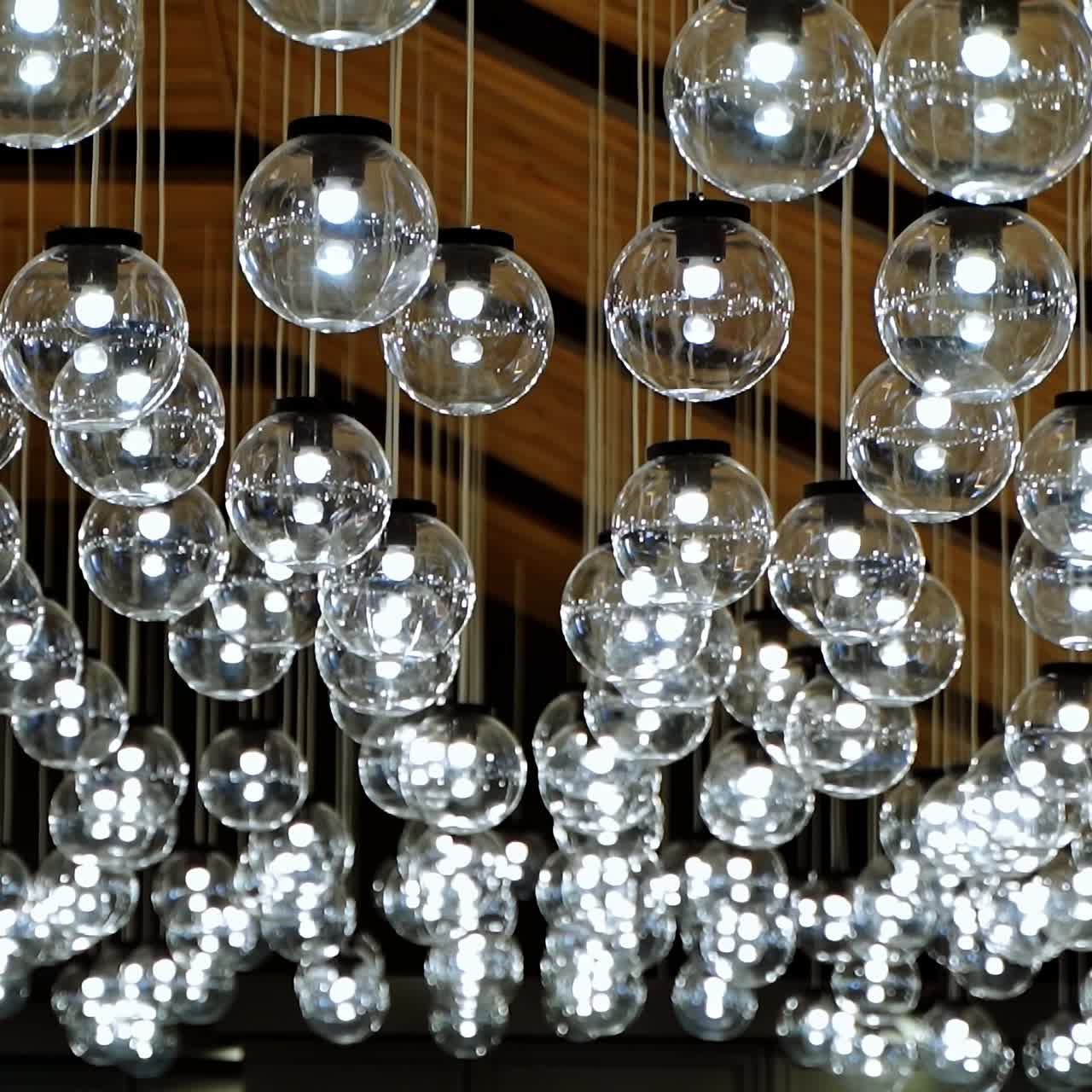 Luxury interior of sparkling lamps. Blurred view of modern ceiling lighting of hanging light bulbs balls indoors.