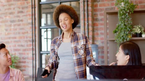 happy biracial creative businesswoman talking with diverse colleagues in casual office, slow motion