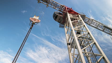 The-hook-block,-trolley-and-chain-of-a-flat-top-construction-crane,-moving-up-to-focus-on-the-cab-and-turntable