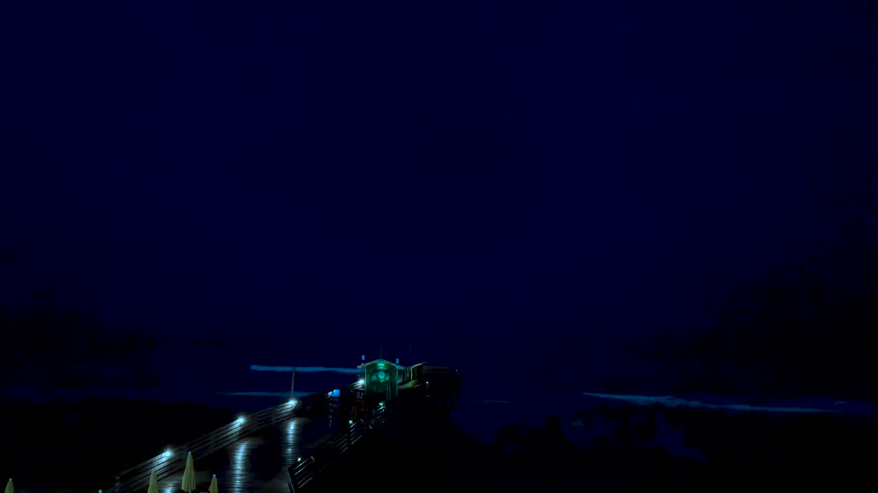 Thunder and lightning during a spring storm on the beach with a pier in the foreground