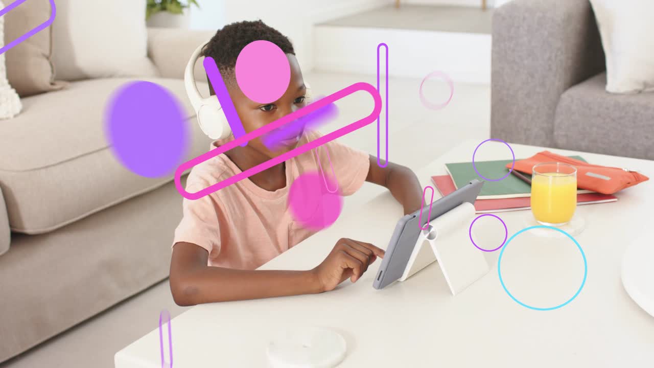 Boy tapping tablet at table, initiating animated education graphics moving across screen and face