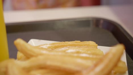 Gebratene-Churros-In-Teller-Mit-Saft-Im-Glas-Hautnah