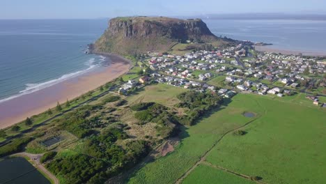 aerial flight over town with huge rock in background in tasmania, australia