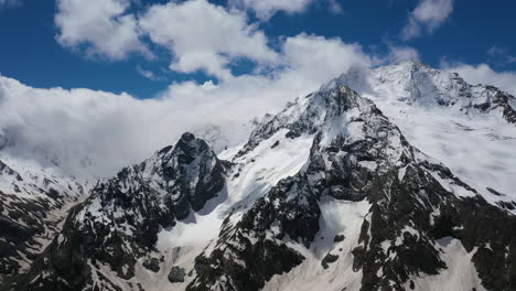 vuelo aéreo a través de nubes montañosas sobre hermosos picos nevados de montañas y glaciares.