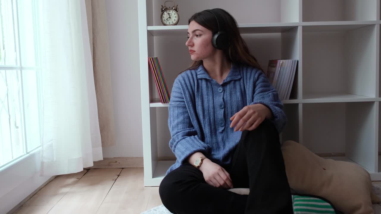 una chica joven se siente triste mientras escucha música con auriculares