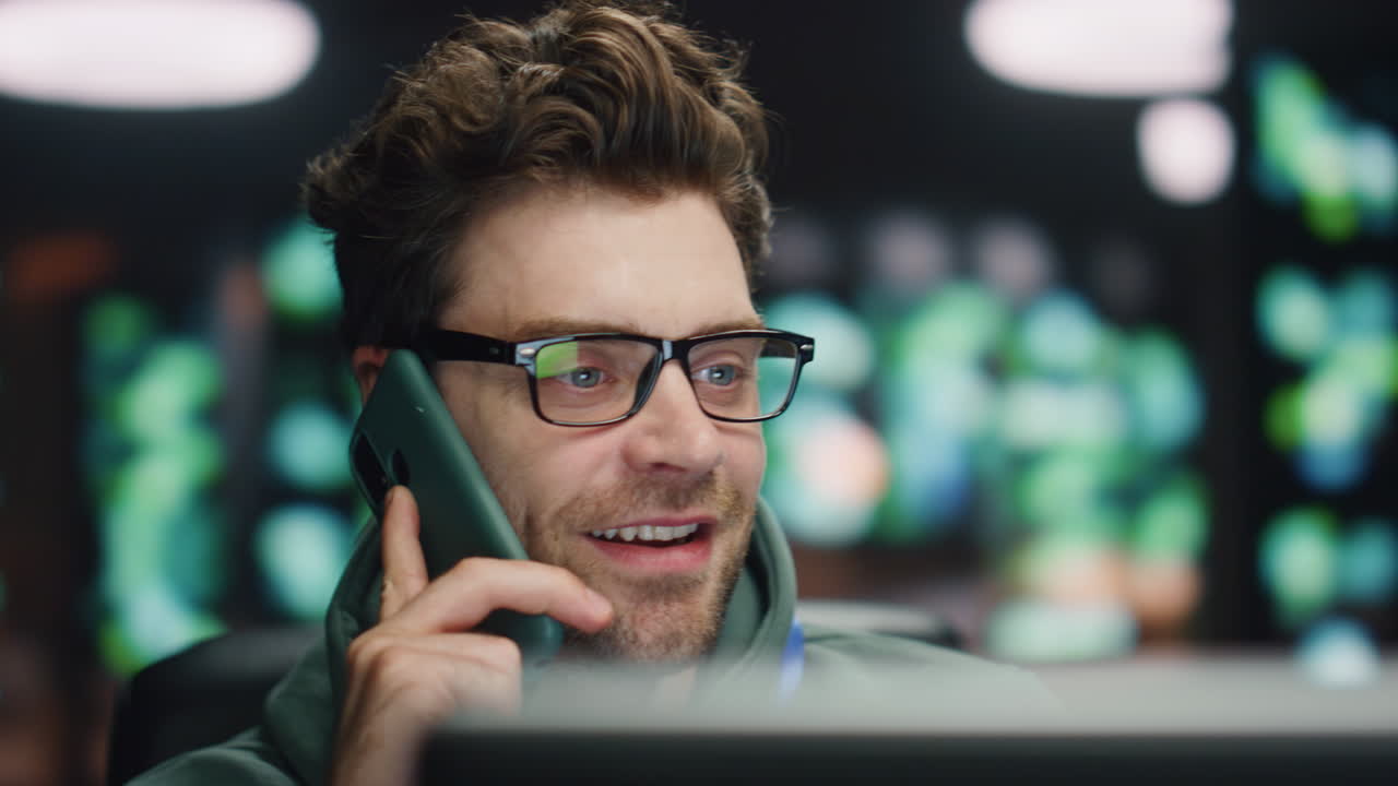 desarrollador feliz hablando teléfono inteligente en la noche centro de datos primer plano. hombre que termina la llamada