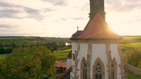 Drohnenflug-Vor-Einer-Kirche-Von-Unten-Nach-Oben-Bis-Zum-Sonnenuntergang-Inmitten-Von-Weinbergen