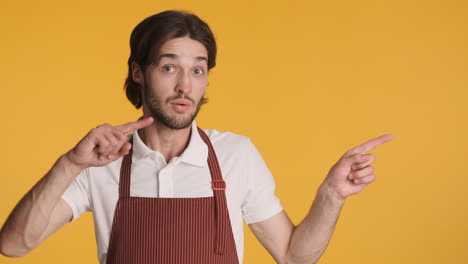 Caucasian-waiter-in-front-of-camera-on-yellow-background.