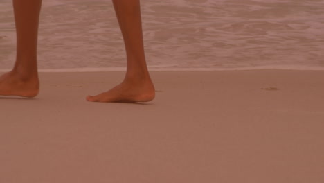 low section of a woman walking at the beach