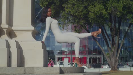 a young girl in a white bodysuit delights in a day in the city, glass buildings behind her