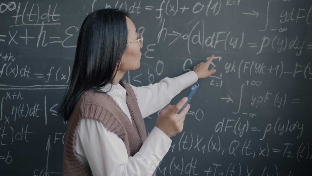 Student using a mobile phone in front of a blackboard full of math equations