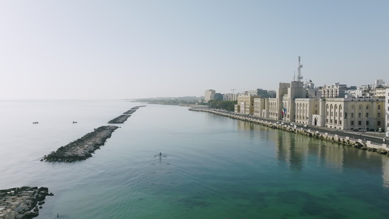 amplias imágenes aéreas del mar adriático frente a la ciudad de bari, italia, con remeros haciendo ejercicio en el agua