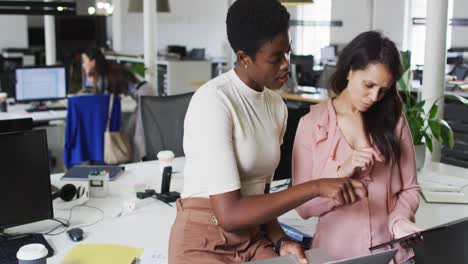 Focused-diverse-businesswomen-working-together-on-laptop-in-office