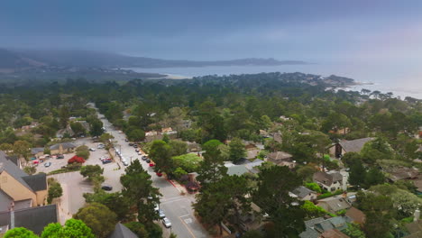 Dramatic dark stormy skies over the beautiful marine city of Carmel, California, USA. Drone flying low over the tree tops.