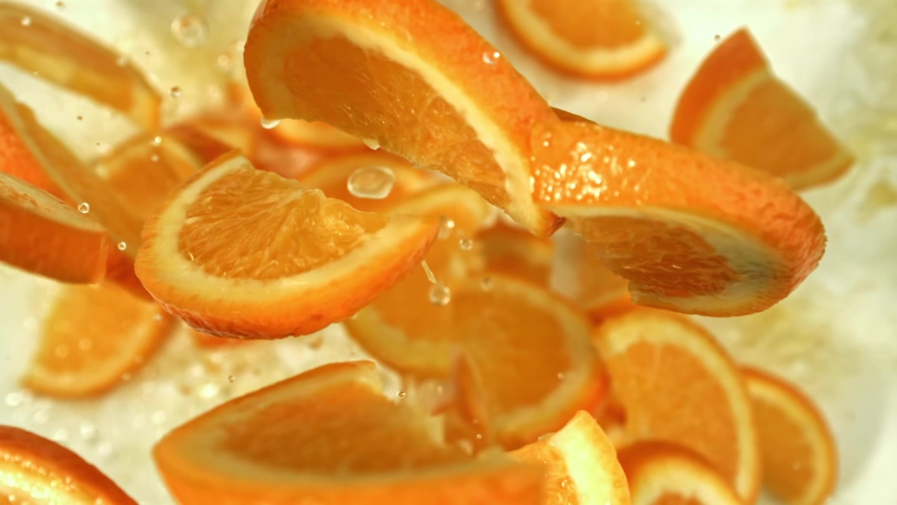 Fette fresche d'arancia che cadono nell'acqua al rallentatore