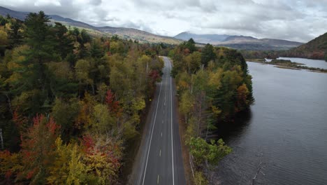 Aerial-View-Of-Road-Along-The-Autumn-Forest-And-Androscoggin-River-In-New-Hampshire,-New-England,-USA