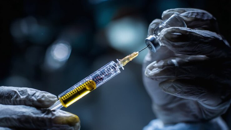 A Close-Up View of a Medical Professional Preparing a Syringe with a Vaccine from a Vial in a Dimly Lit Environment, Highlighting Precision and Care