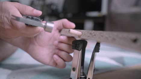 Handyman sinking a dowel pin into a predrilled hole on the furniture with a hammer to make it more steady inside his living room in the house