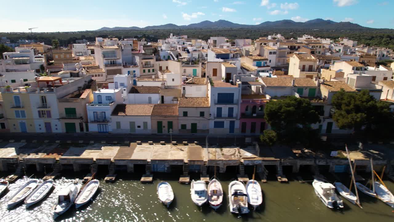 Houses built in typical Mallorcan architectural style directly adjacent to a harbor