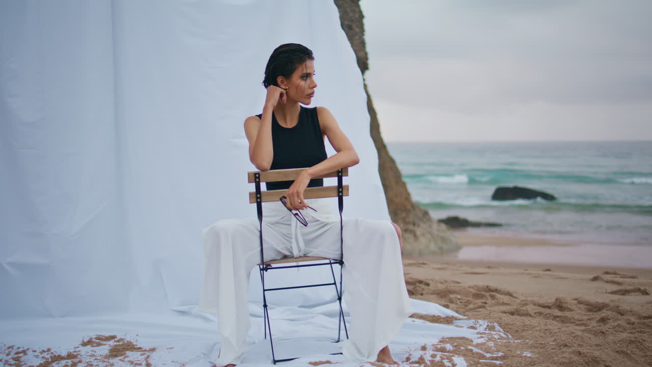 멋진 갈색 여성이 야외에서 해변을 촬영합니다. 섹시한 매혹적인 소녀가 카메라에 포즈를 취합니다.