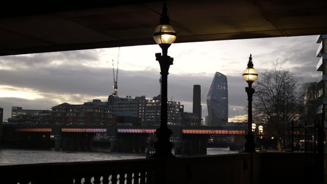 Victorian streetlight illuminate the sidewalk next to Thames with city view